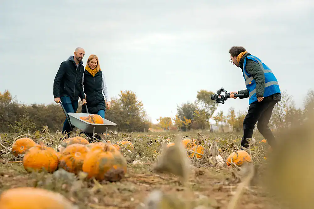 High-quality autumn pumpkin harvest filming scene. Filmmaker recording joyful visitors in pumpkin patch.