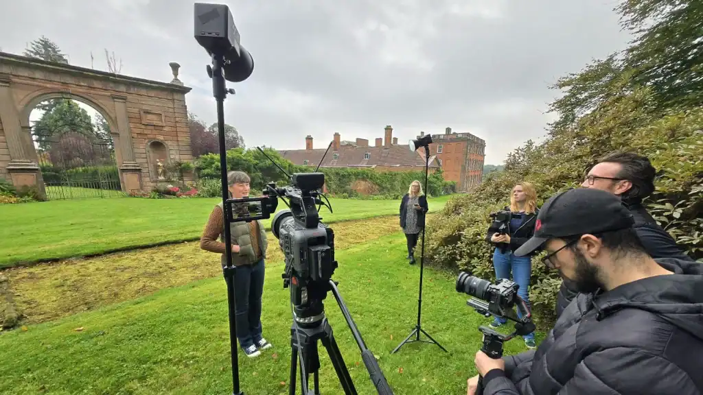 Film crew filming outdoors at historic site in England.